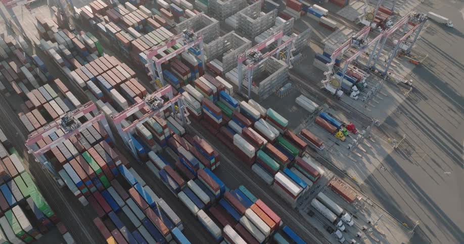 The harbor has many shipping containers and trucks traveling out