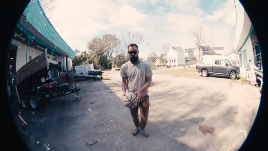 A man with a basketball in the parking lot in a neighborhood