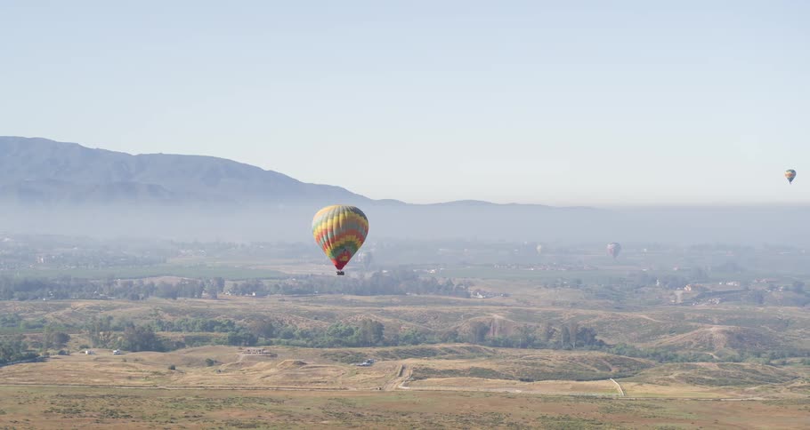 A hot air balloon flying over a rural town during the day
