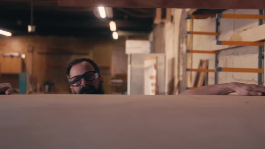 Man taking a wooden sheet from an indoor shed