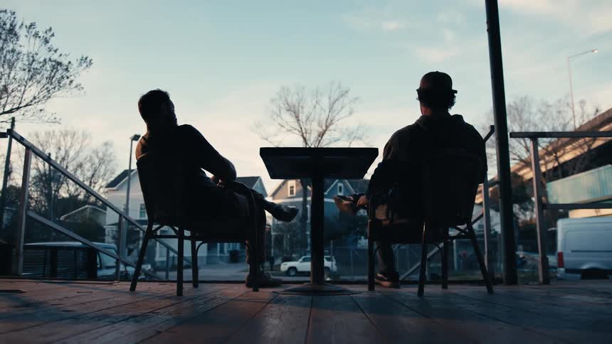 Silhouette of two friends talking while sitting on the porch