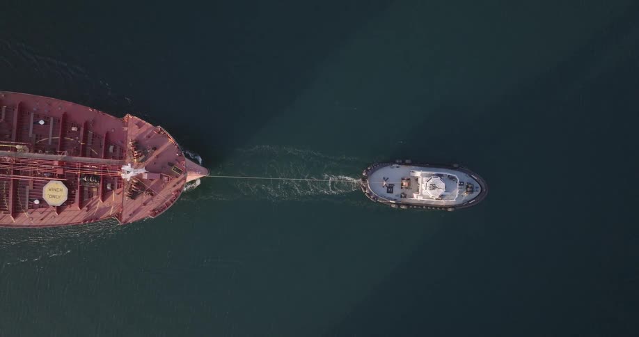 Aerial view of a ship pulling a cargo ship in the middle of the sea
