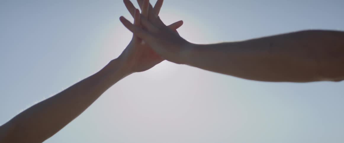Sunlight shines through interlocked hands