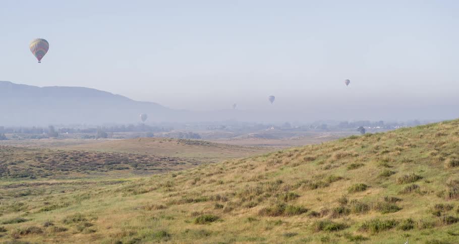 Three balloon parachutes in the air on a sunny day