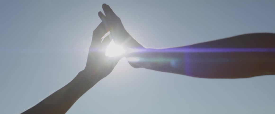 Couple touching hands intertwining fingers against a backdrop of a sunny sky