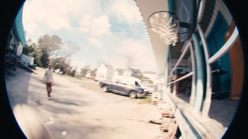 Fisheye lens shot of a man playing basketball in the parking lot