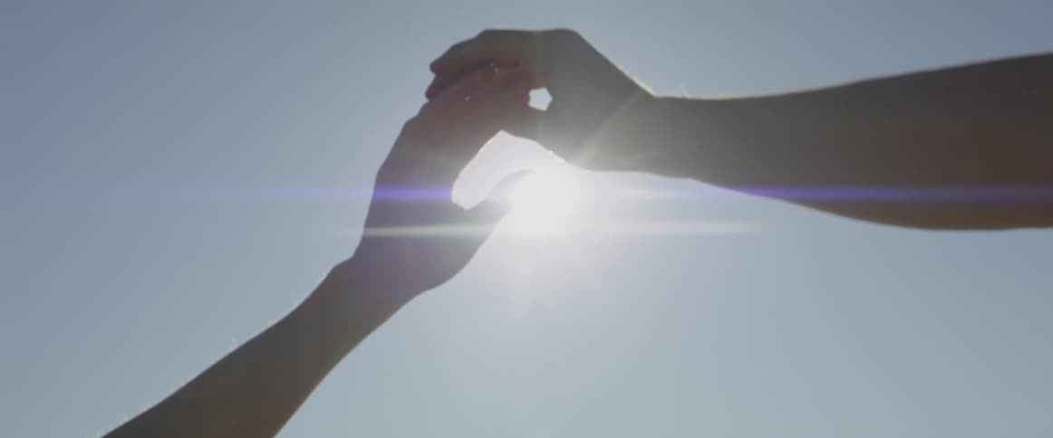 Sunlight shines through interlocked hands