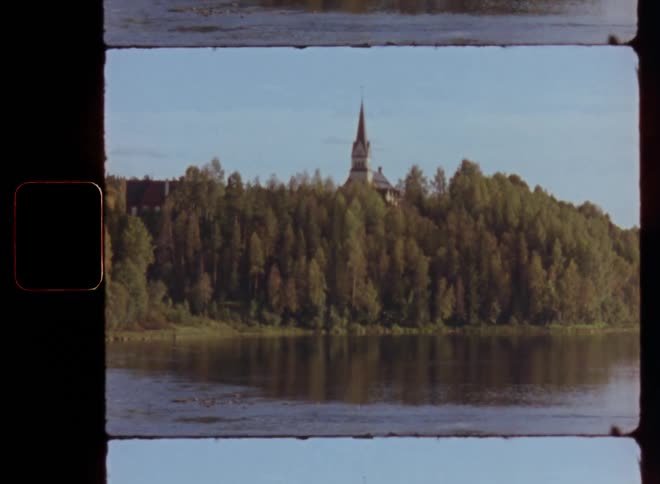 Church tower over the forest next to a lake