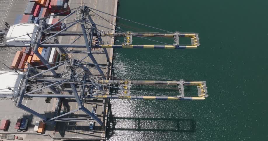 The aerial view of a port with cranes and containers shows a busy maritime hub for global trade