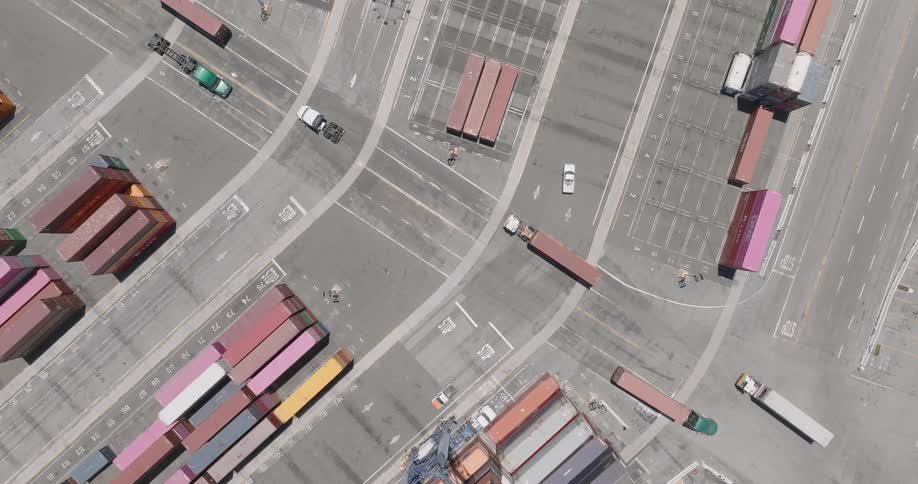 An area with many trucks transporting containers on an asphalt street