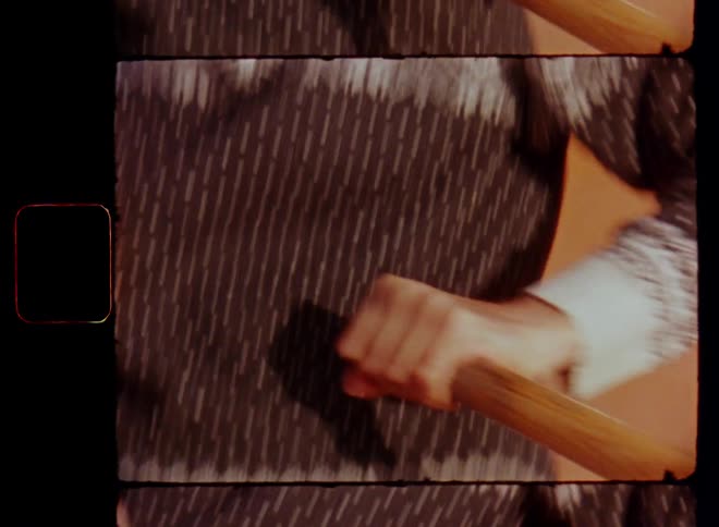 Hand-held Super 8mm close-up of the hands of a man with knitted pullover and woolen hat holding the oars or paddles or a canoe while rowing the boat over a lake or body of water in warm sunlight on a sunny day