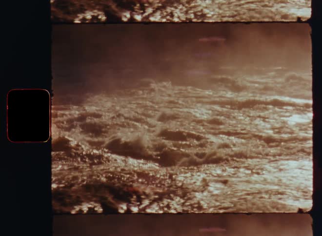 Churning water flows past muddy shore on hazy day
