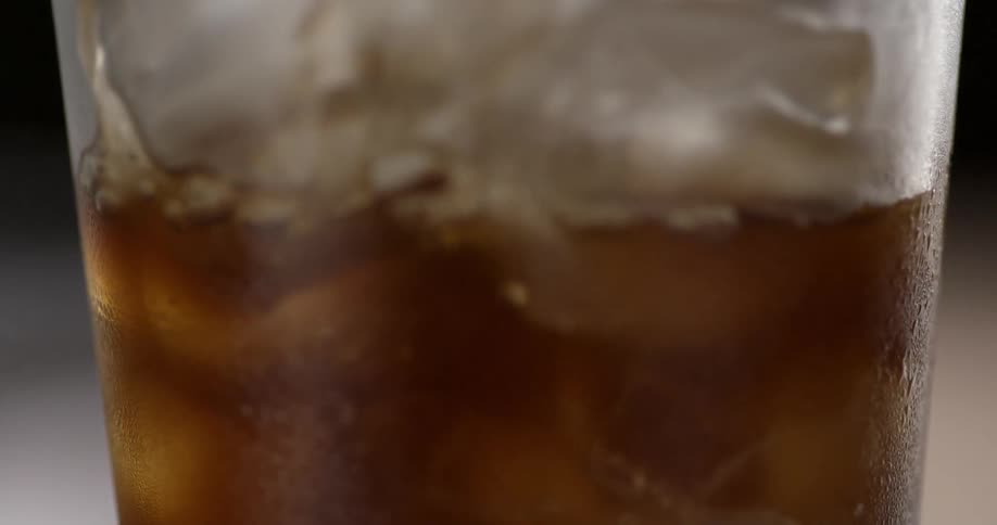 A glass full of ice is being filled