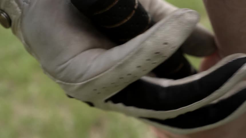 A person tightens his grip on a golf club