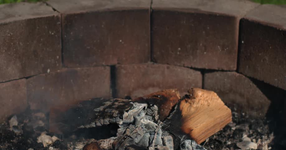 A fire pit is out with smoke rising from the ashes
