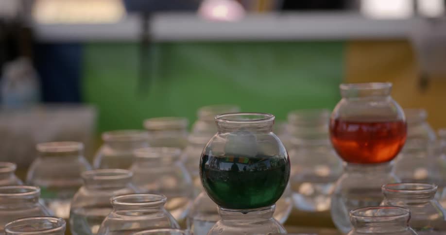 A ping pong ball is thrown into a jar of green liquid
