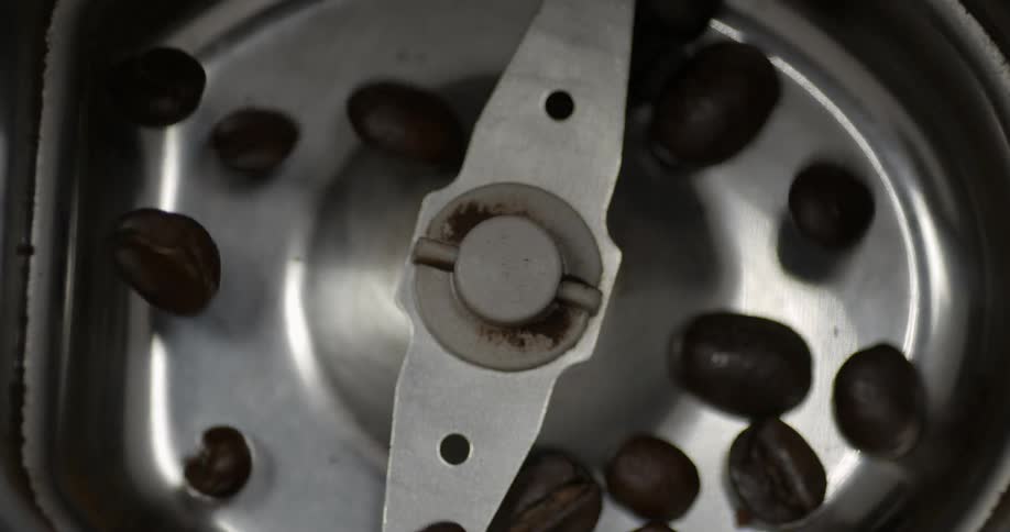 Coffee beans falling into a coffee grinder