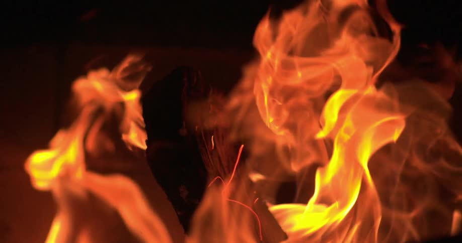 A fire rages burning wood at night