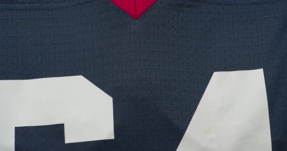 Someone pulls a jersey down over their football equipment