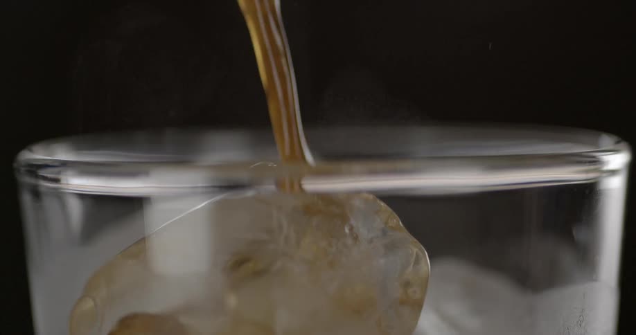A glass with ice is filled with a drink