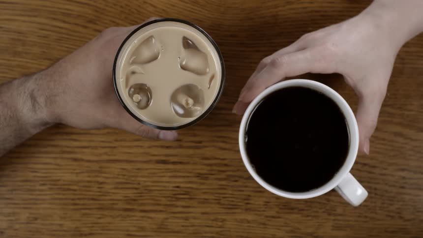 A person slides a glass with ice over to a mug