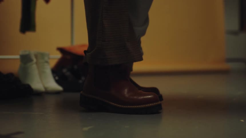 A person placing a foot in a brown formal boot
