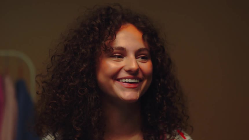 Young girl with curly hair and orange paint on her face making funny faces and laughing