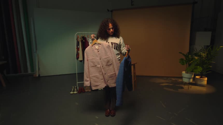 A girl in an empty room choosing fashionable clothes