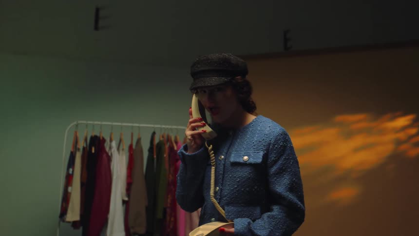A lady on the telephone in a room filled with designers cloth