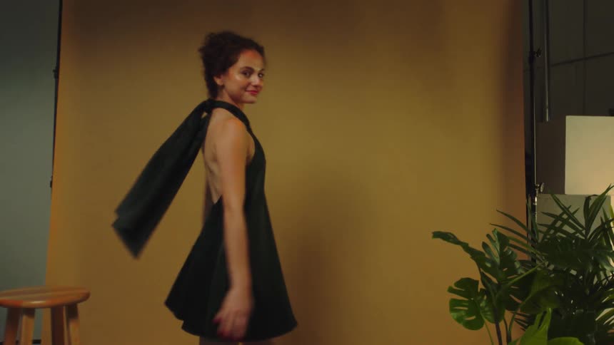 Teen models a black armless gown in a room