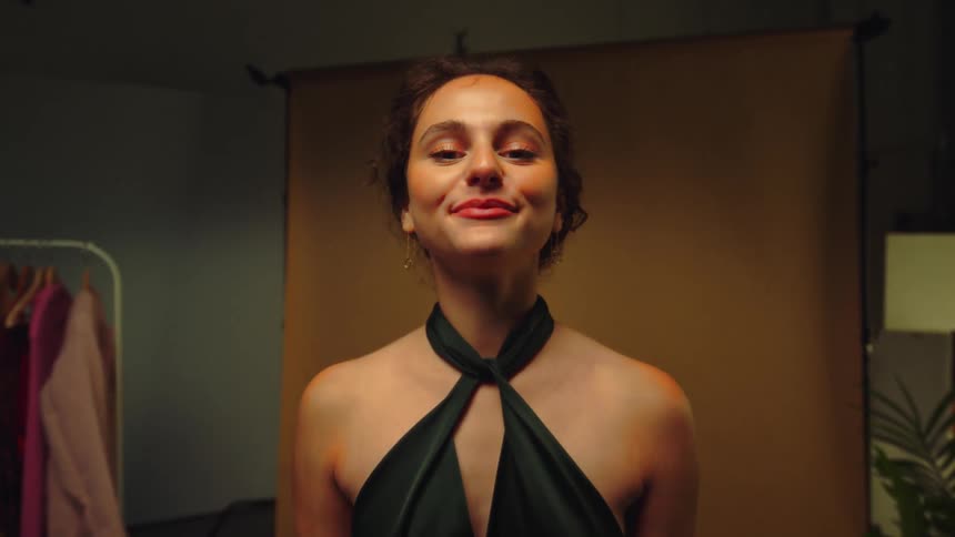 A young woman in an elegant dress smiles while posing