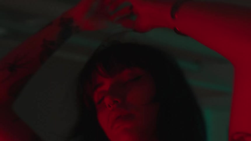 Woman dances in room lit by blue and red colored lighting