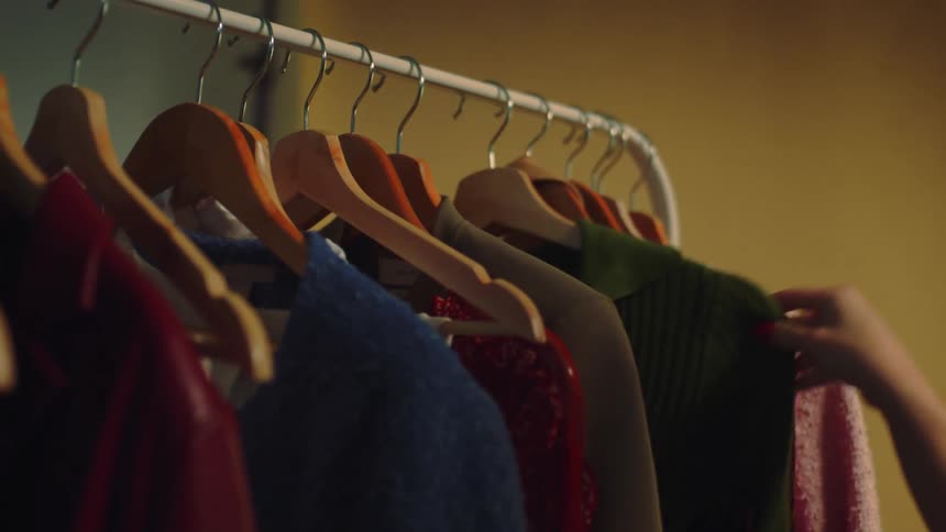 A person choosing a sweater to wear
