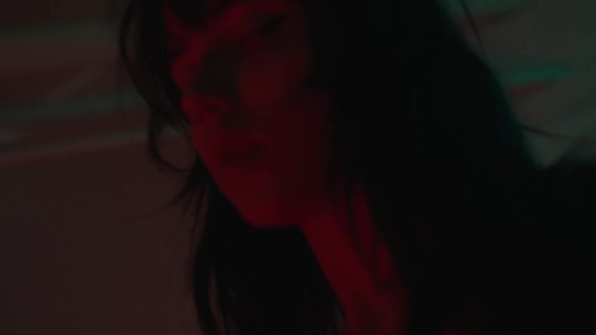 Closeup on the face of a woman dancing in a dark environment with red lights shining on her face