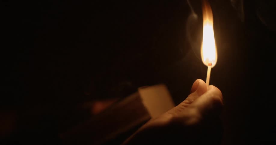 A person lights a match in a pitch black room