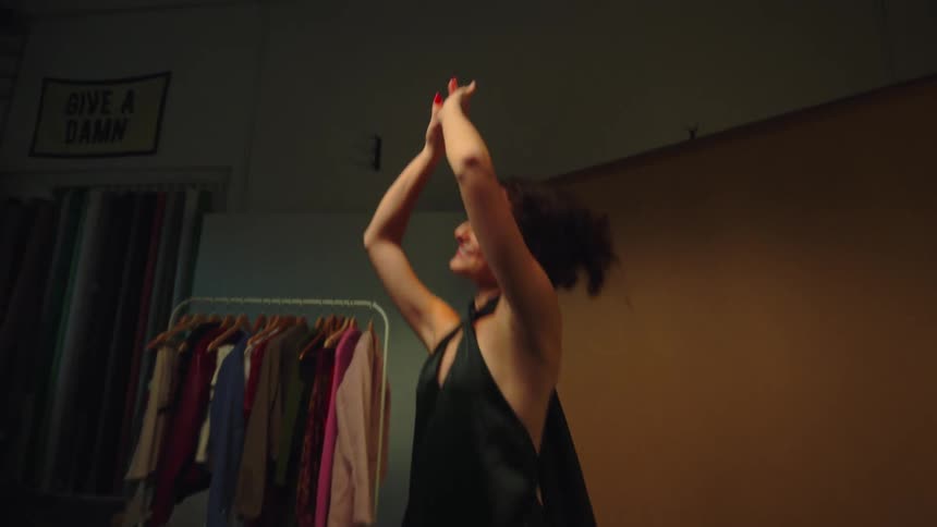 Young adult woman dancing and smiling alone indoors in a room during day light