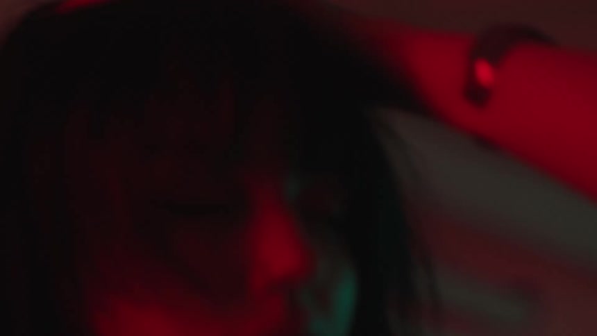A woman is dancing under flashing lights