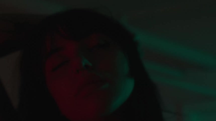 Close up of the face of a woman dancing in a room with red lights