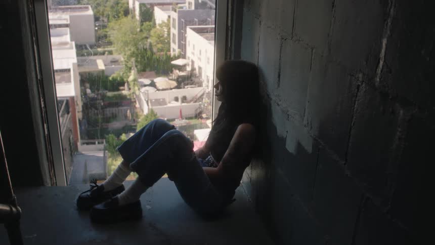 A girl is sitting by the window in the hall