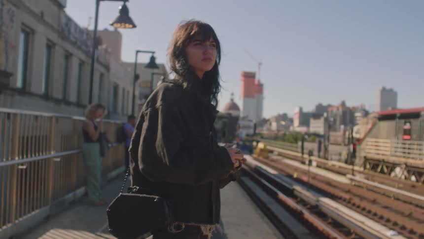 A footage of a girl and some people waiting at the train station