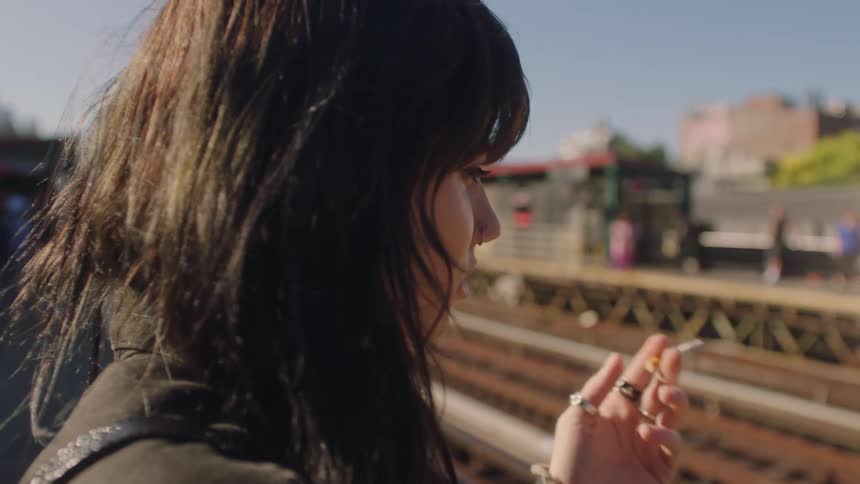 Portrait of a young woman smoking at a train station
