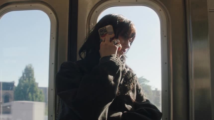 A woman leaning against the door of a moving train