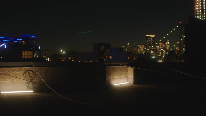 Woman stands on the roof of a building in the city at night