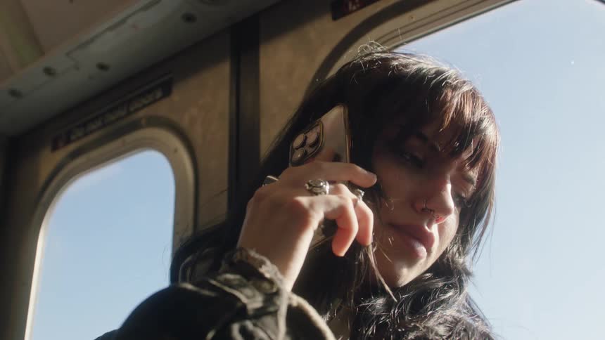 A woman clad in a black jacket engages in a phone call while riding the subway seamlessly blending into the daily urban hustle