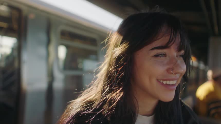 A young woman sitting in a train station talking and laughing