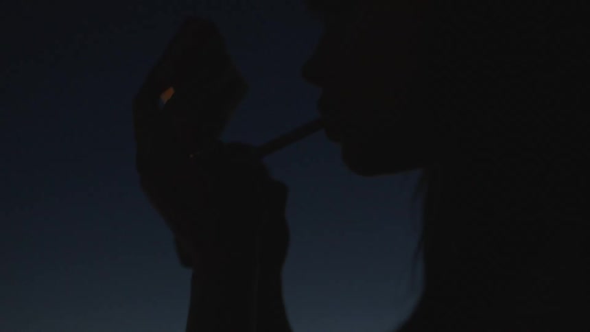 A woman smoking on a roof of a building at night
