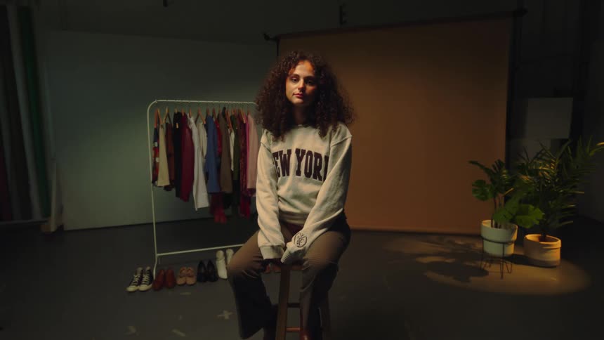 A girl sitting on a wooden bench in an empty room