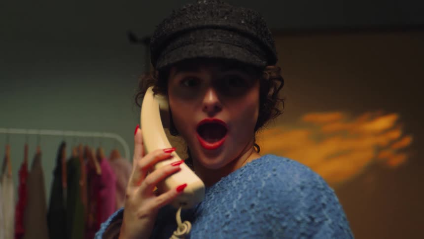 A woman on the phone in a room filled with fashion clothes