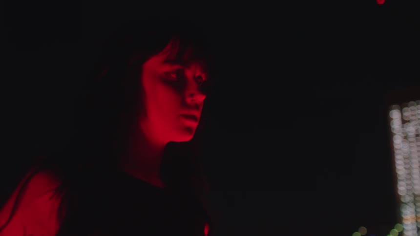 Portrait of a woman with a distressed facial expression in an outdoor setting at night