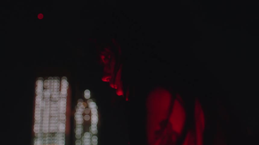 Woman pants while turning side to side and stands under red lighting
